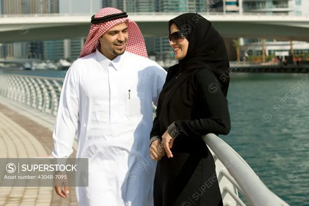 Arab couple standing by the railing in Dubai Marina, UAE