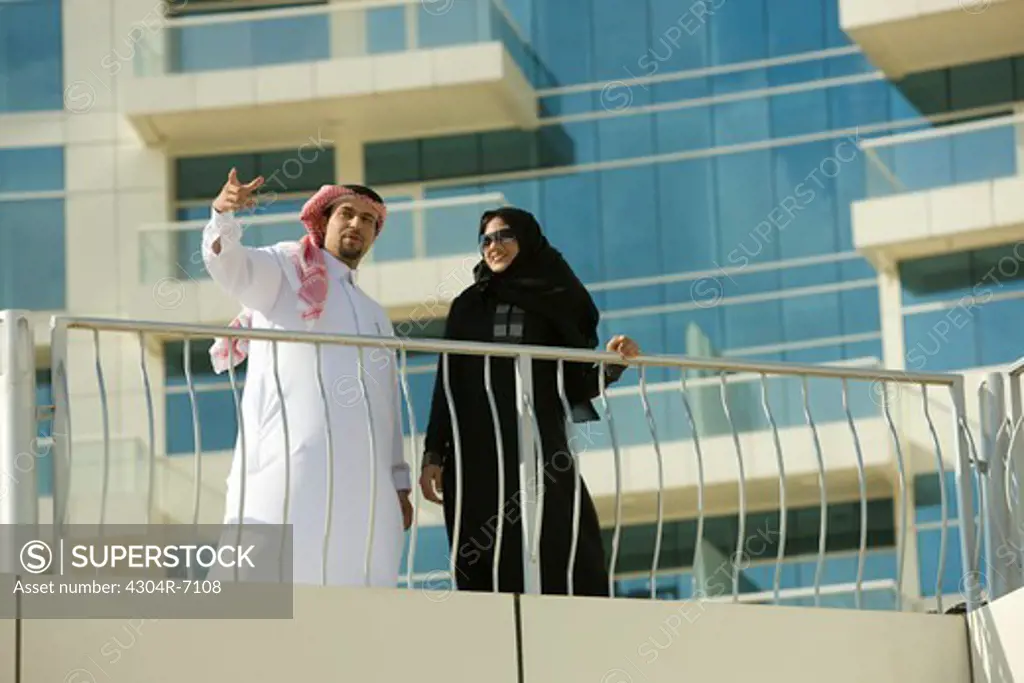 Arab couple standing by the railing of a building at Dubai, UAE