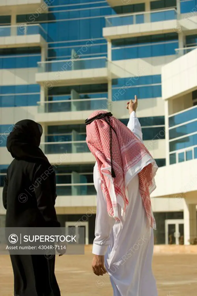 Arab couple looking up at a building at Dubai Marina, UAE