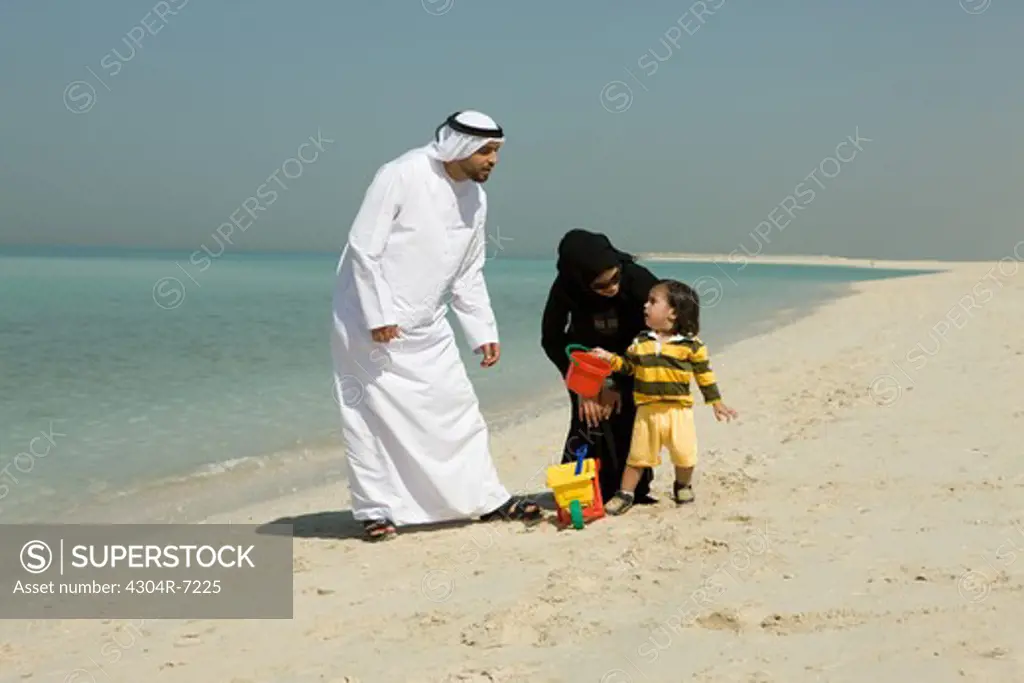 Arab couple playing with their son at the beach
