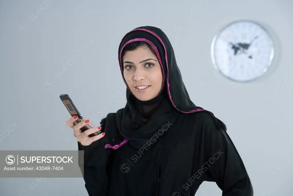 Arab woman holding a cellphone, smiling