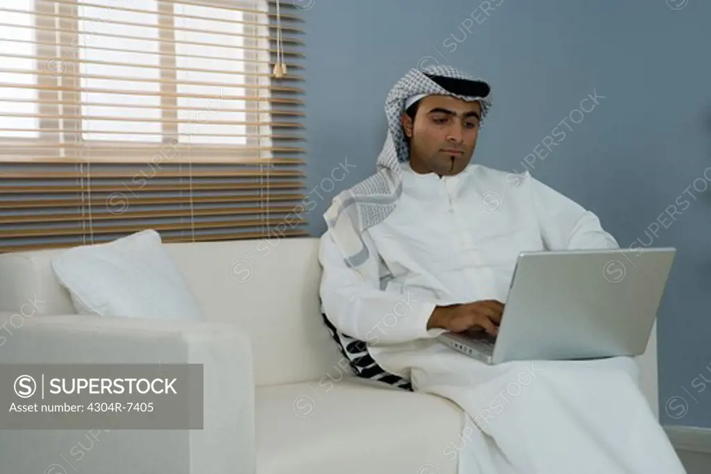 Arab man with laptop sitting on a sofa