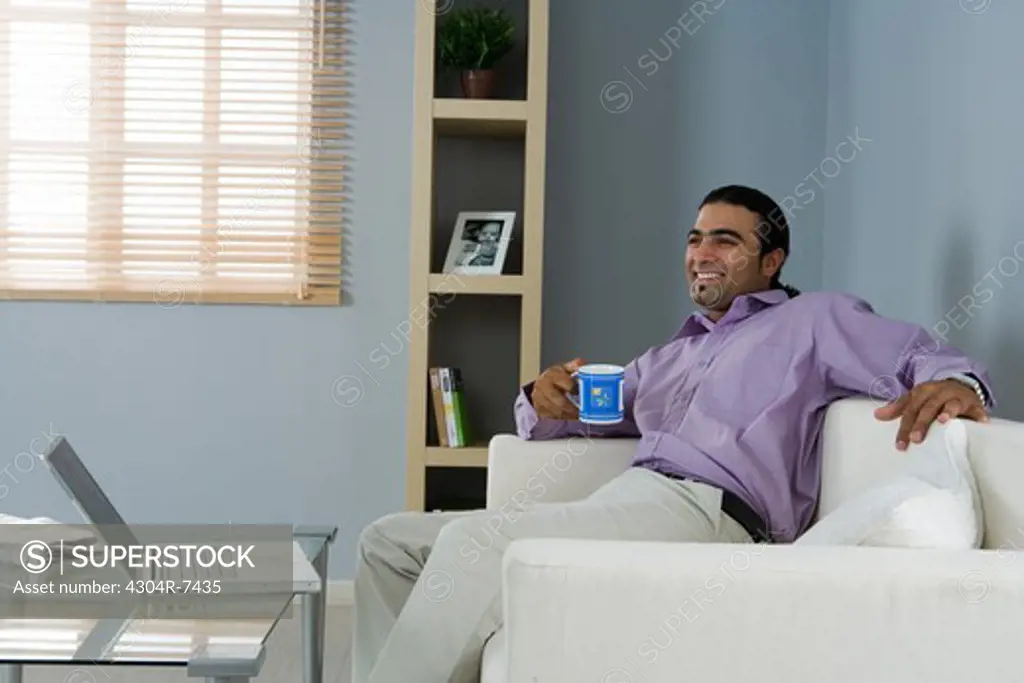 Man holding cup, sitting in the living room