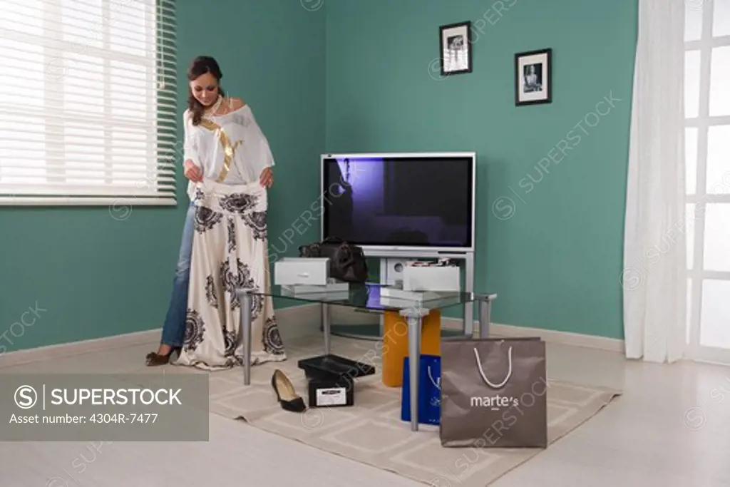 Woman in the living room with shopping bags holding a skirt