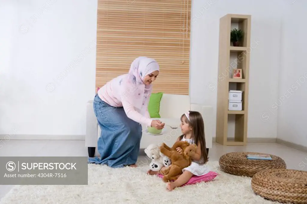 Mother feeding her daughter in the living room