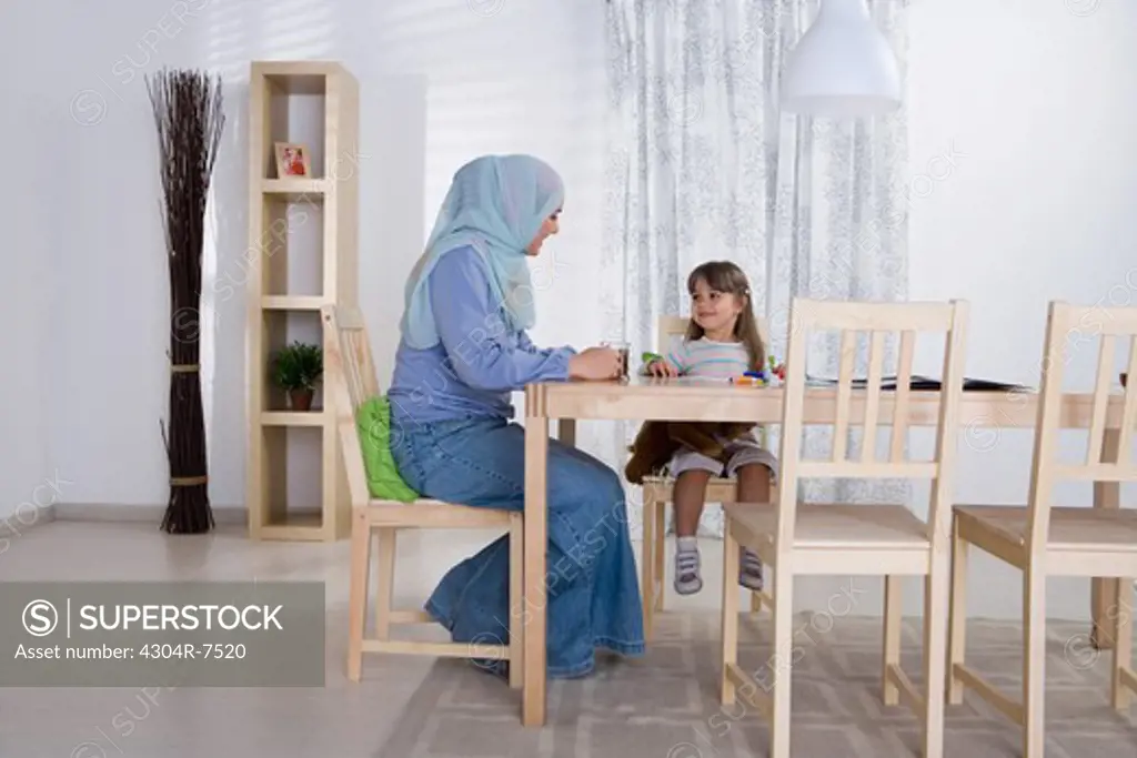 Arab mother helping her daughter with homework