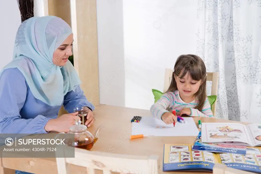 Arab mother helping her daughter with homework