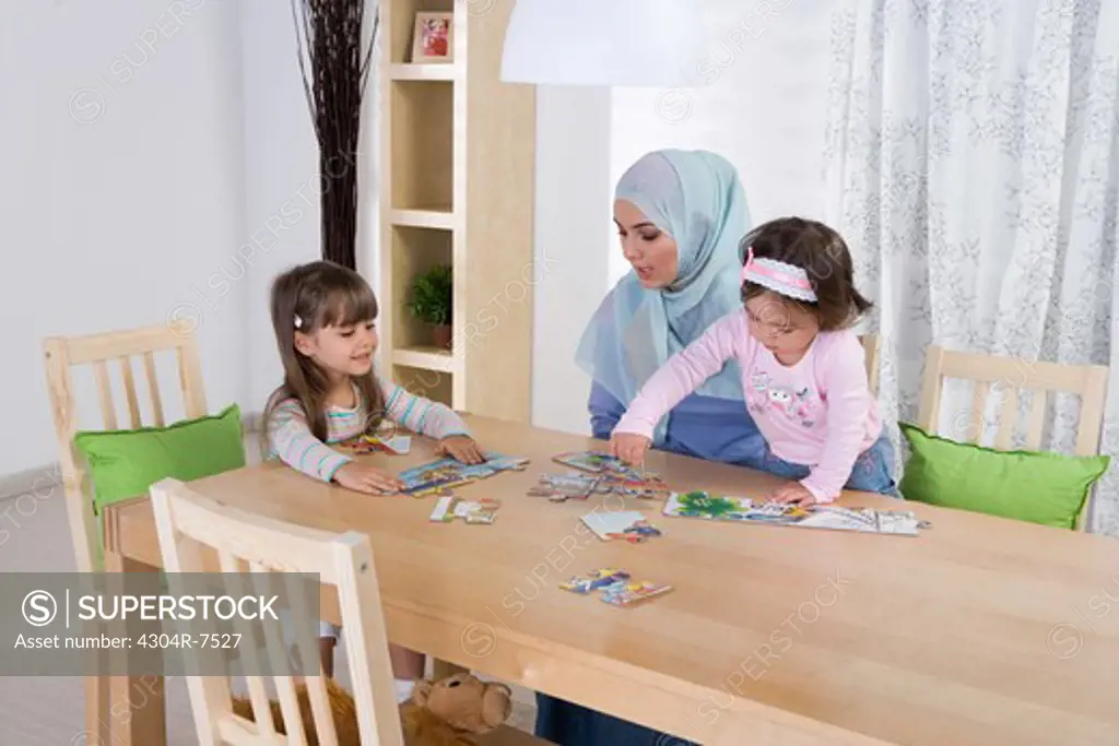 Arab mother with two daughters putting puzzle together