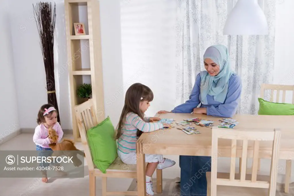 Arab mother with two daughters putting puzzle together
