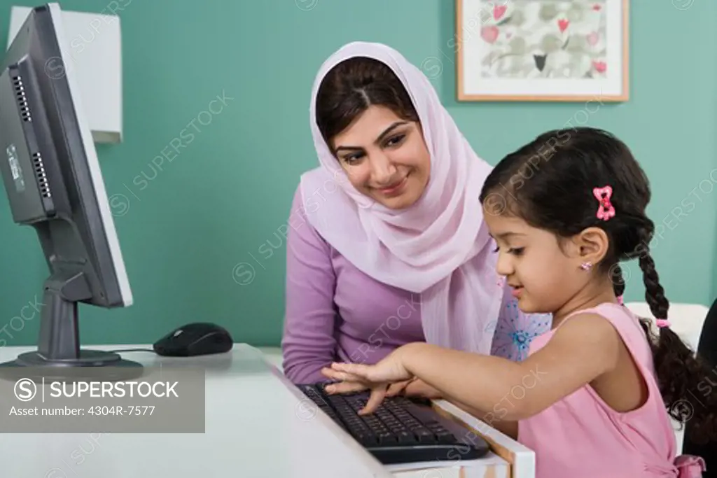 Arab mother and daughter in front of a computer