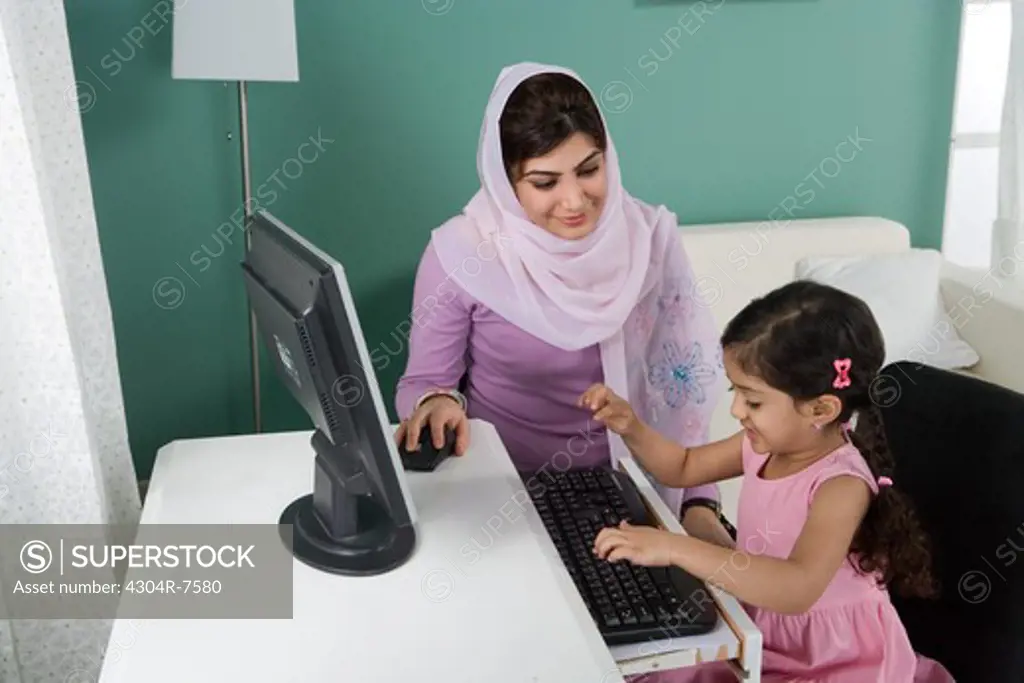 Arab mother and daughter in front of a computer