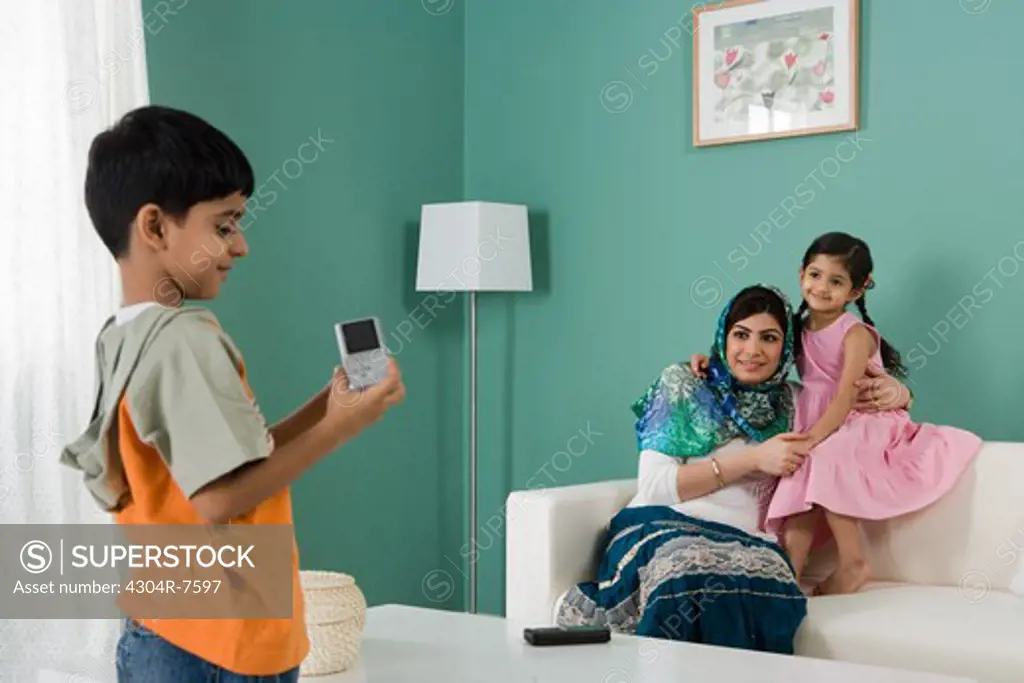 Boy taking photo of his mother and sister in the living room