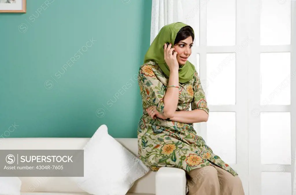 Arab woman using cellphone in the living room