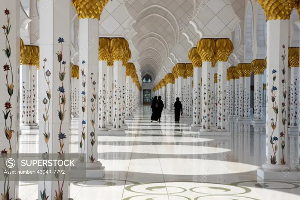 Three women wearing abaya, walking in Sheikh Zayed Mosque, Abu Dhabi, UAE
