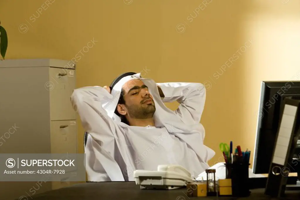 Arab man sitting with hands behind head