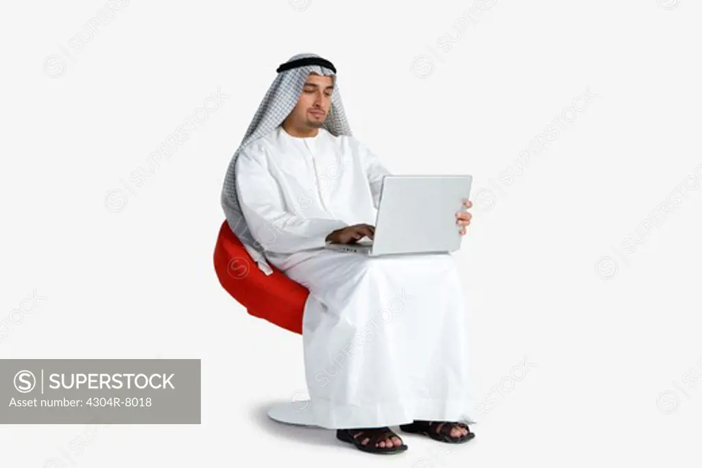 Young man sitting on chair, using laptop