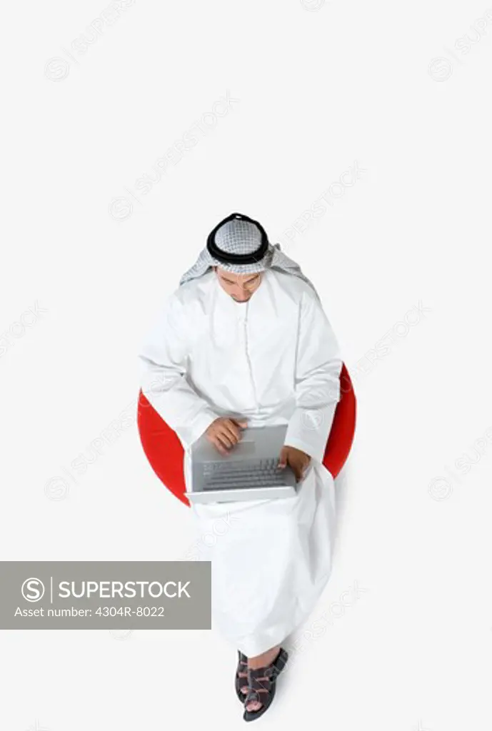Young man sitting on chair, using laptop, top view