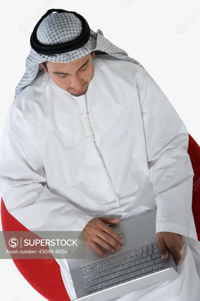 Young man sitting on chair, using laptop, elevated view