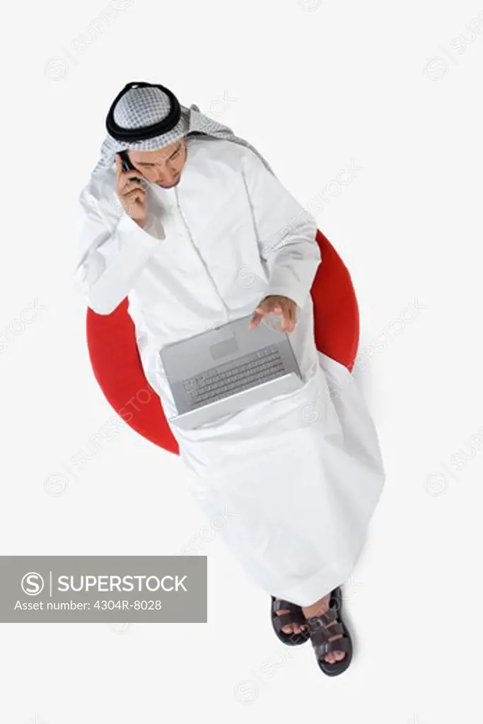 Young man on the phone, using laptop, elevated view