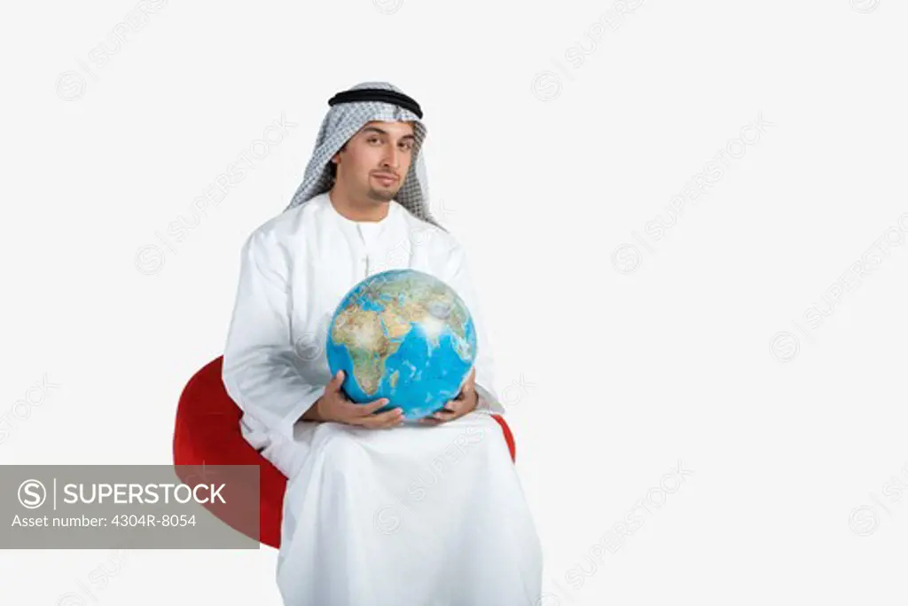 Young man sitting on chair, holding globe, portrait