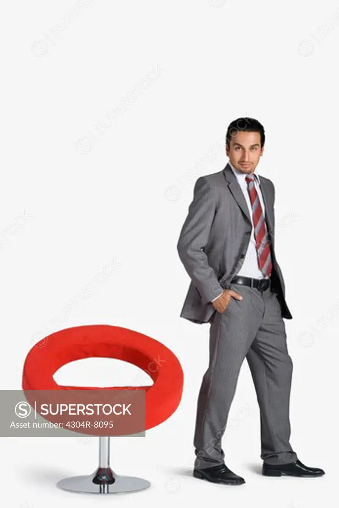 Young businessman standing by swivel chair, portrait