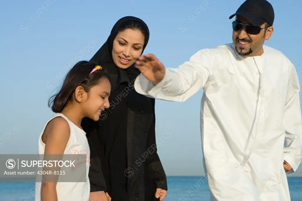 Girl with parents on beach, smiling, side view