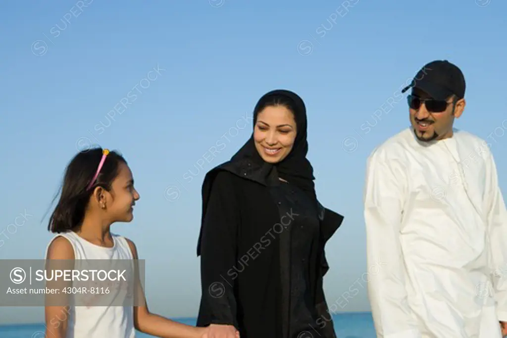 Girl with parents on beach, smiling, side view