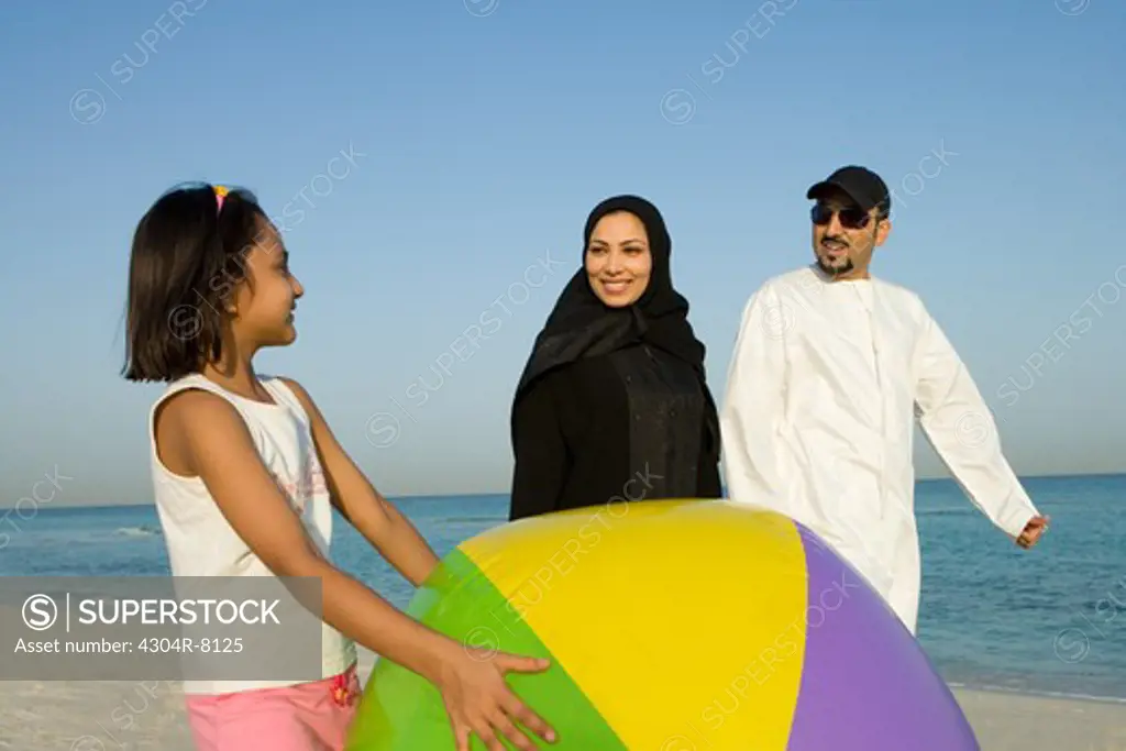Girl holding beach ball while parent looking at her