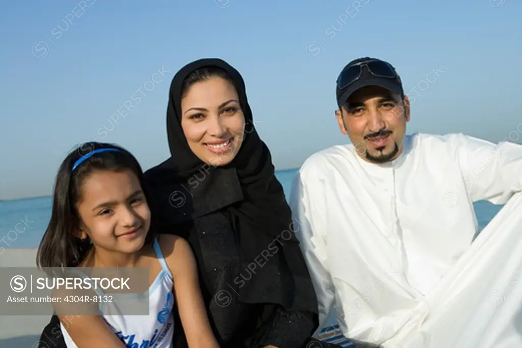 Girl with parents on beach, smiling, portrait