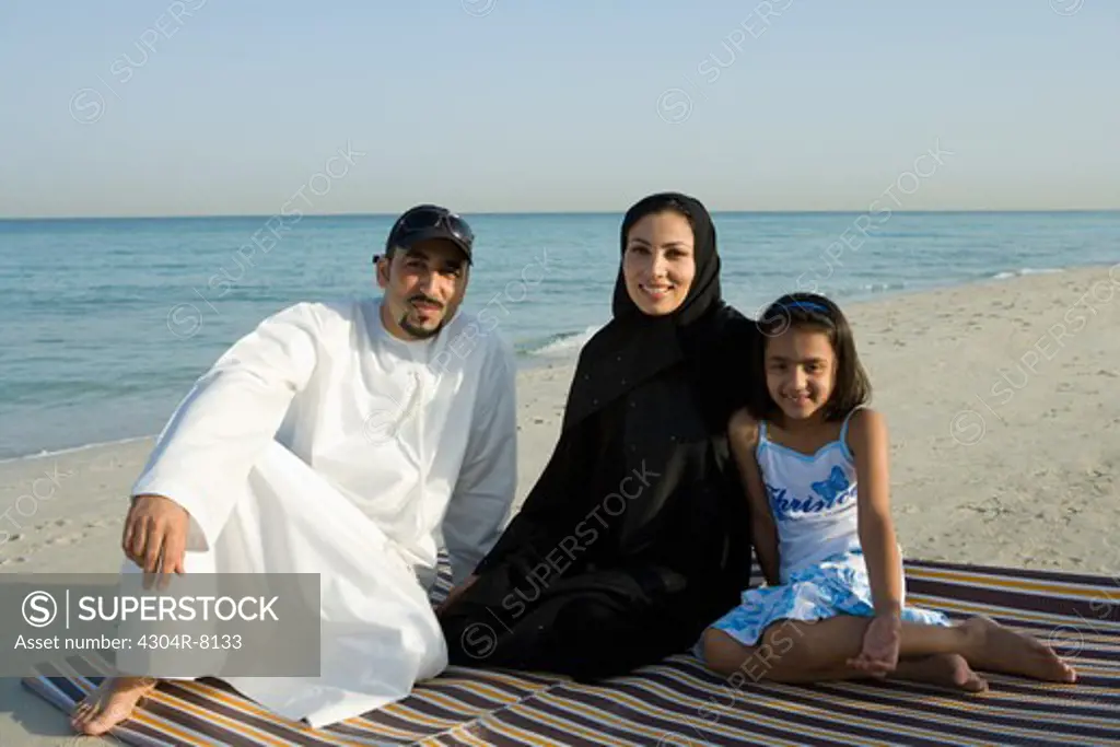 Family sitting on beach, smiling, portrait