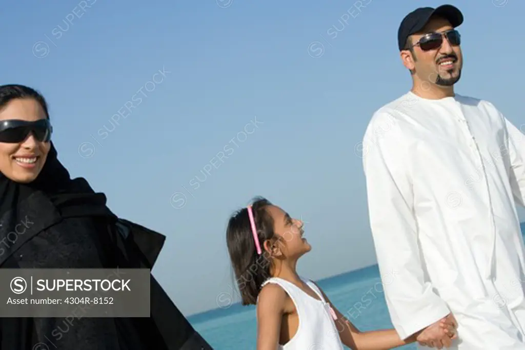 Girl with parents on beach, smiling
