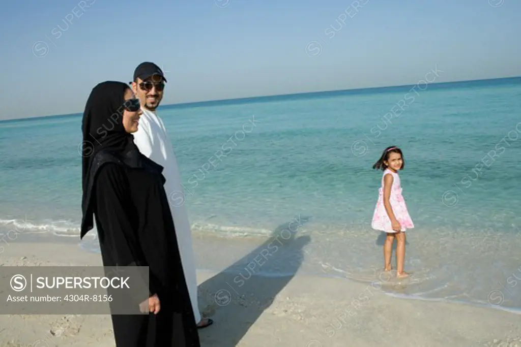 Young couple with daughter on beach, side view