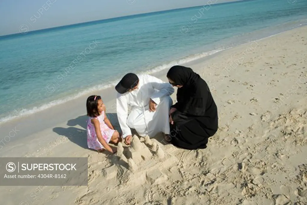 Girl playing with parents in sand, elevated view
