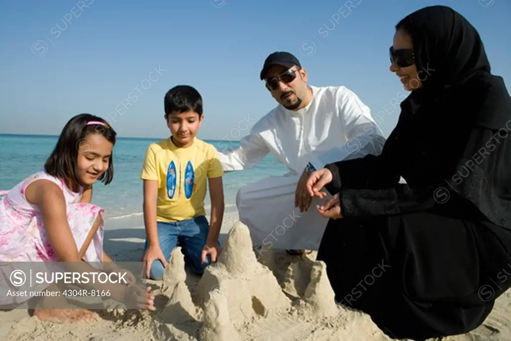 Son and daughter playing with parents in sand
