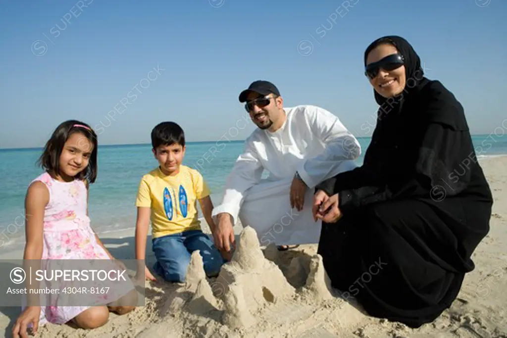 Son and daughter playing with parents in sand, portrait