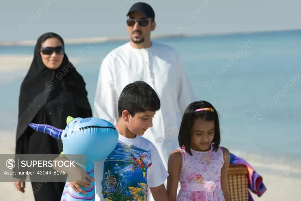 Family walking on beach, smiling