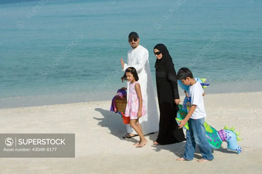 Family walking together on beach, smiling