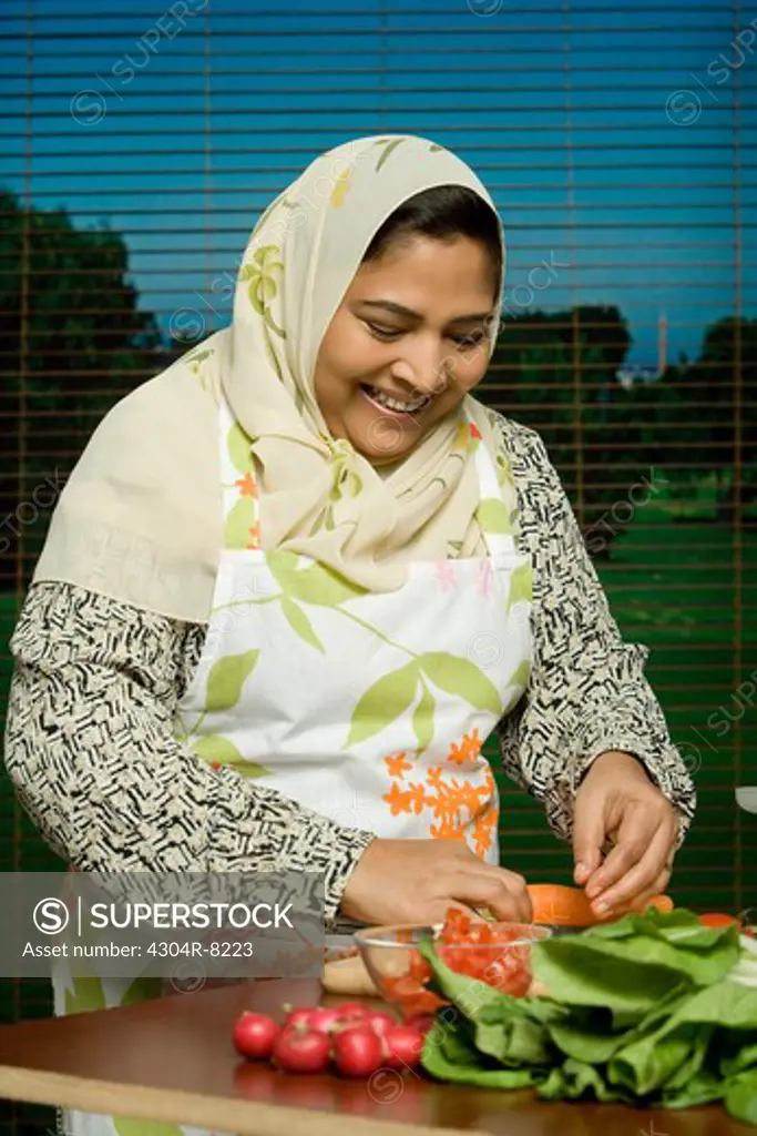 Mid adult woman chopping tomatoes, smiling