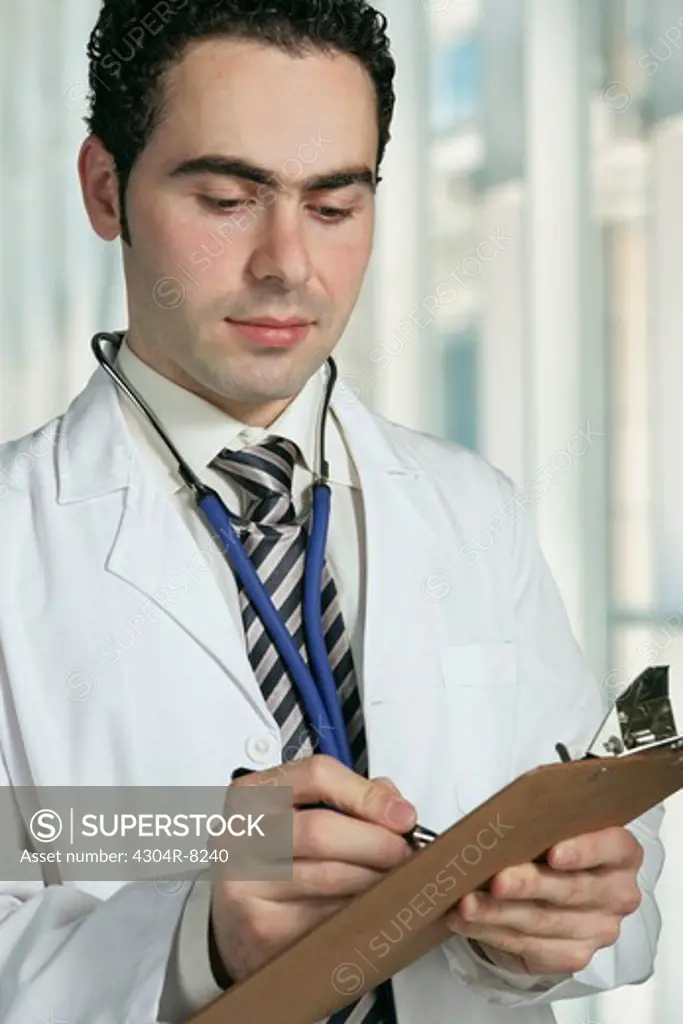 Doctor writing in medical record.