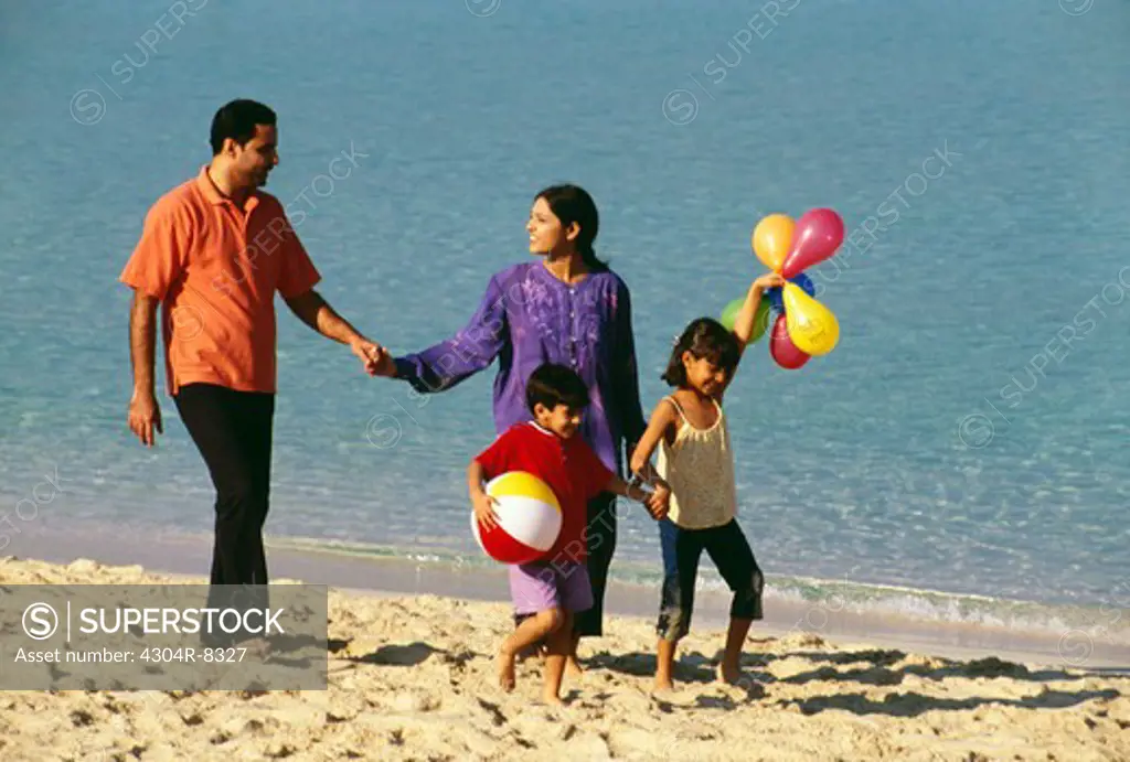 A family takes a stroll at the beach on a sunny day.