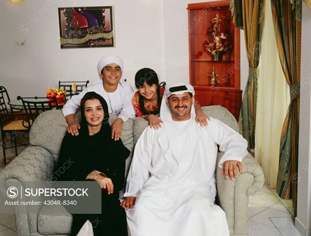 A happy Arabian family gather in front of the camera for a family picture.