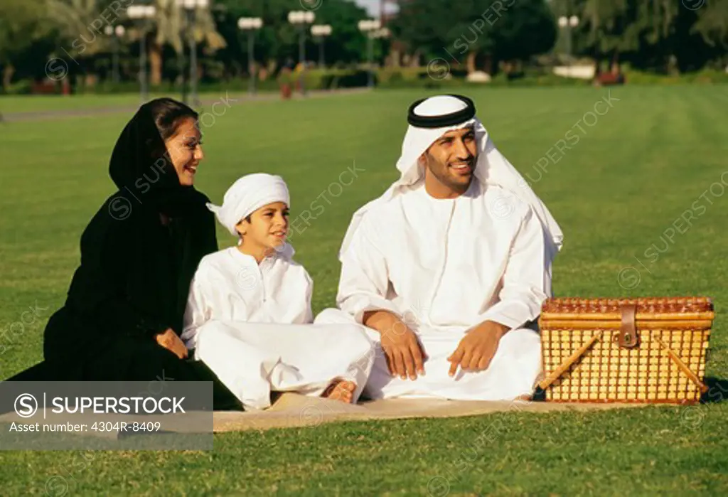 A boy with his mother and father is enjoying the outing in the park.