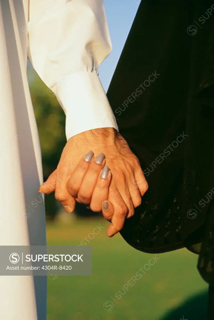 A couple clasping each others hand is seen at close up.
