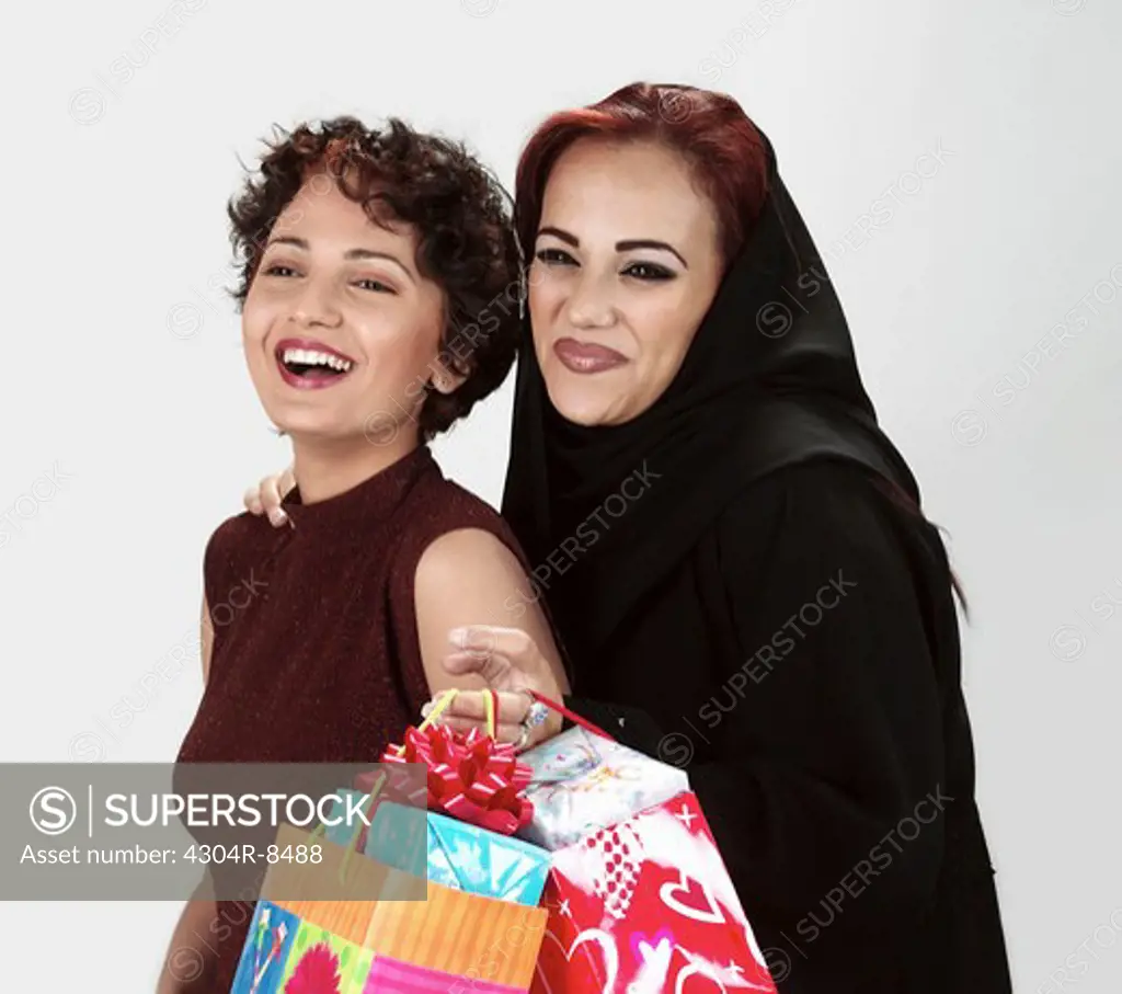 Two women holding shopping bags & laughing