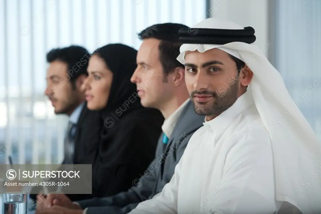 Multi-ethnic business people listening in a conference, arab businessman looking at the camera.