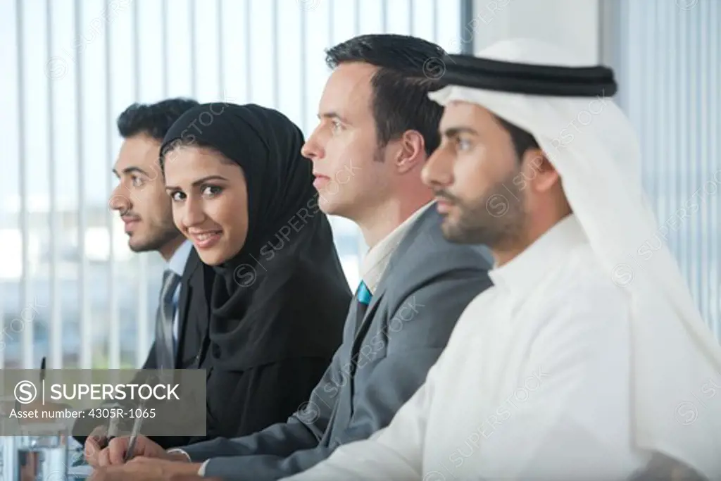 Multi-ethnic business people listening in a conference, arab businesswoman looking at the camera.