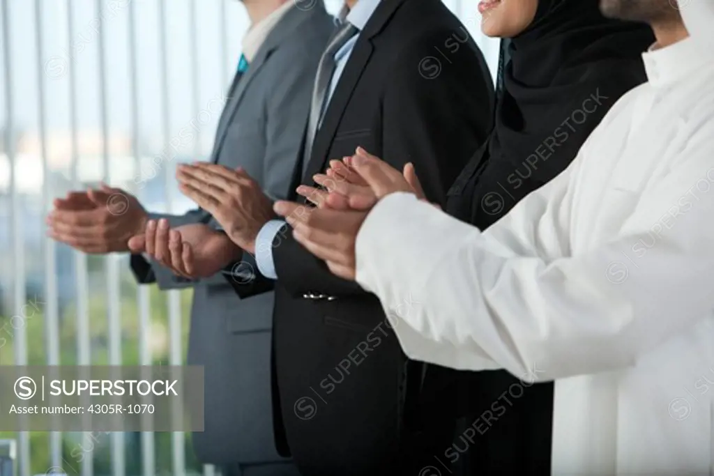 Multi-ethnic business people clapping in a conference, smiling.