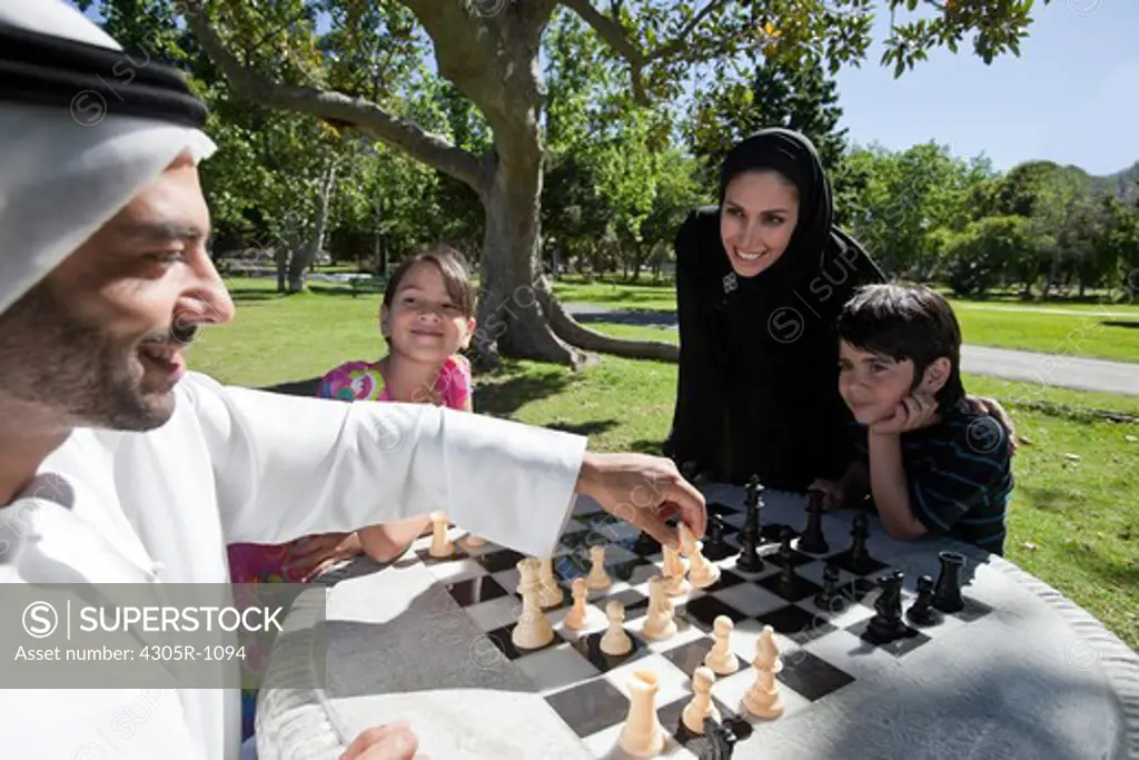 Arab family playing chess together at the park.