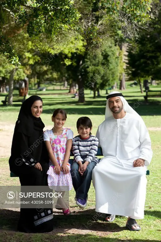 Portrait of an arab family sitting together at the park, smiling.