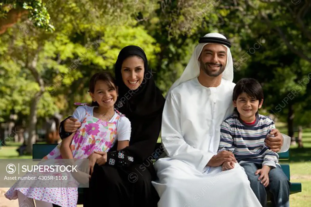 Portrait of an arab family sitting together at the park, smiling.